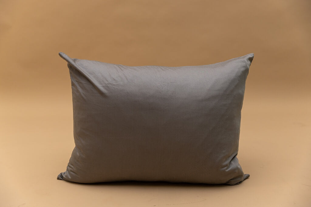 A gray zipper pillowcase displayed on a tan backdrop.