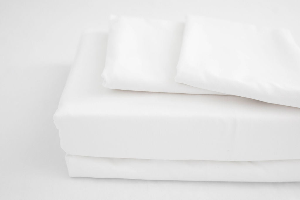 A close up view of a folded white zipper sheet set.