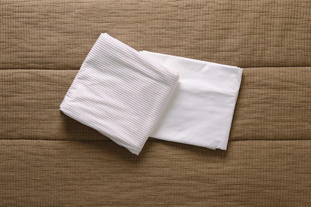 White minky and cotton replacement ZipTop pieces folded on brown bedding.