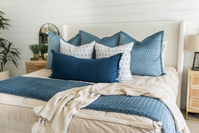 Tan zipper bedding styled with blue, white and tan pillows and tan and blue blankets