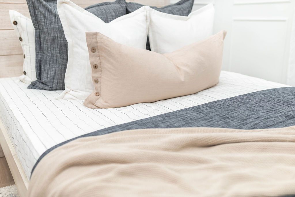White zipper bedding with white, grey and cream pillows and grey and tan blankets