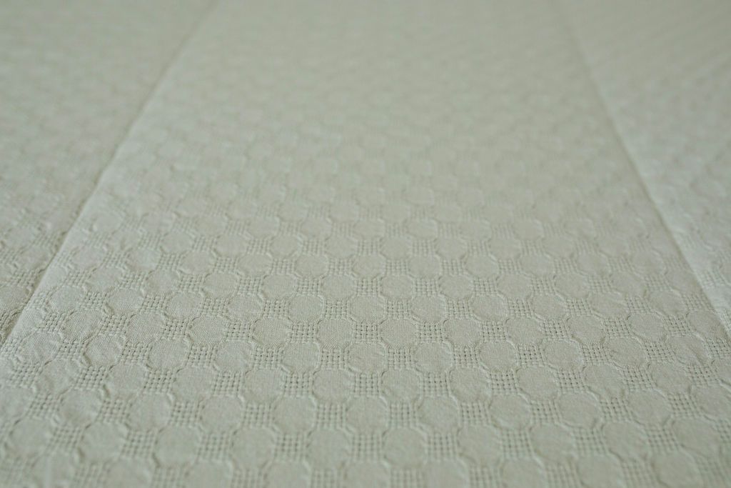 Close up detailed view of light sage green zipper bedding texture