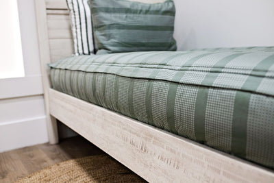 side of twin bed with green striped bedding