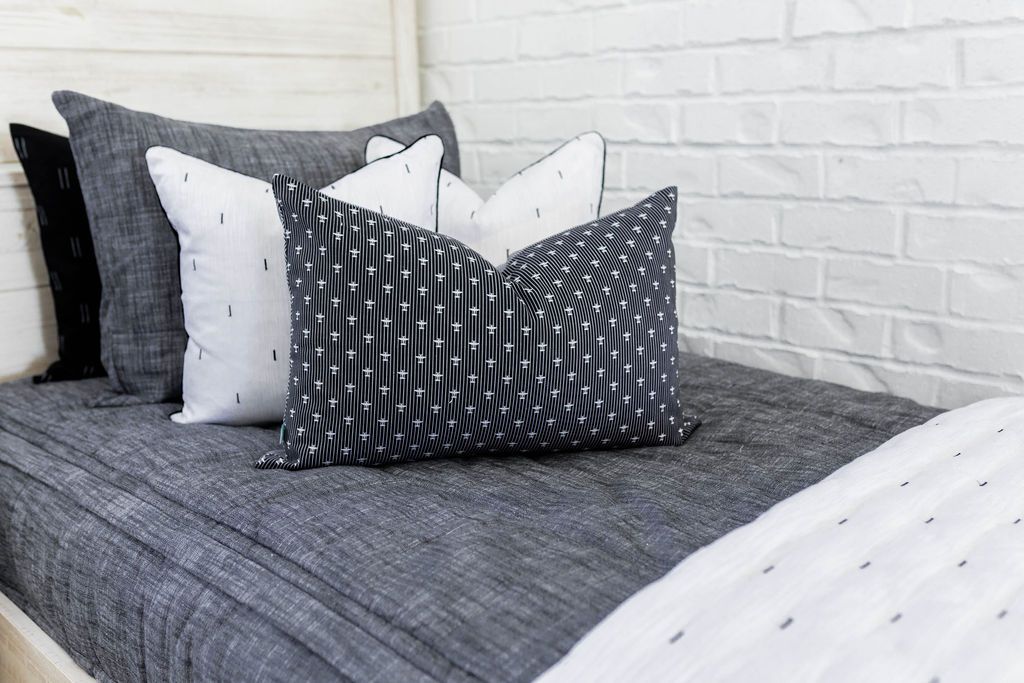 Gray charcoal zipper bedding with gray, black and white pillows and white blanket