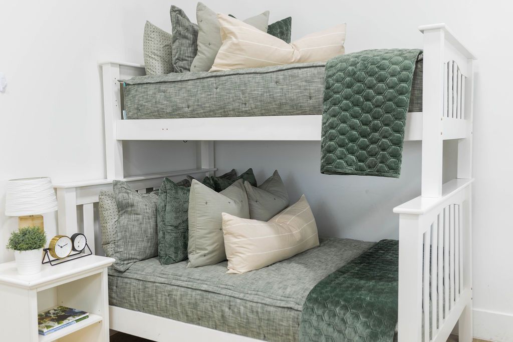 Bunk bed with Green zipper bedding with matching pillows, green velvet hexagon pattern pillow and matching blanket, and cream lumbar pillow