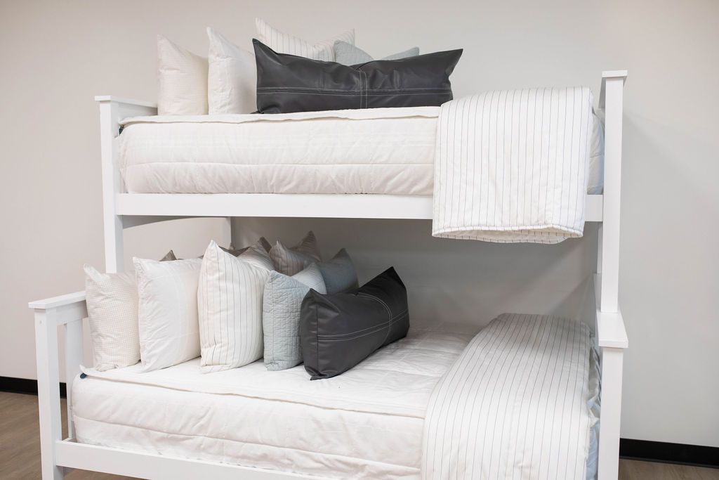 Bunk beds with white zipper bedding styled with white blanket and white, teal and black pillows