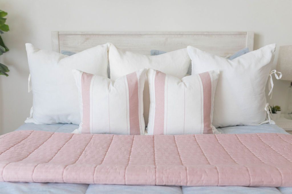 White medium pillow cover with pink vertical stitching design on blue zipper bedding with matching pillows 