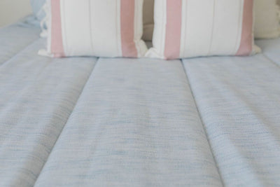 Light blue zipper bedding styled with matching white, blue and pink pillows