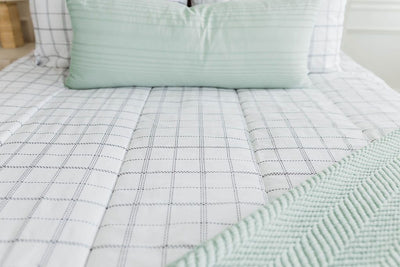 White and black grid patterned textured bedding with sage green extra long lumbar and sage green chenille throw