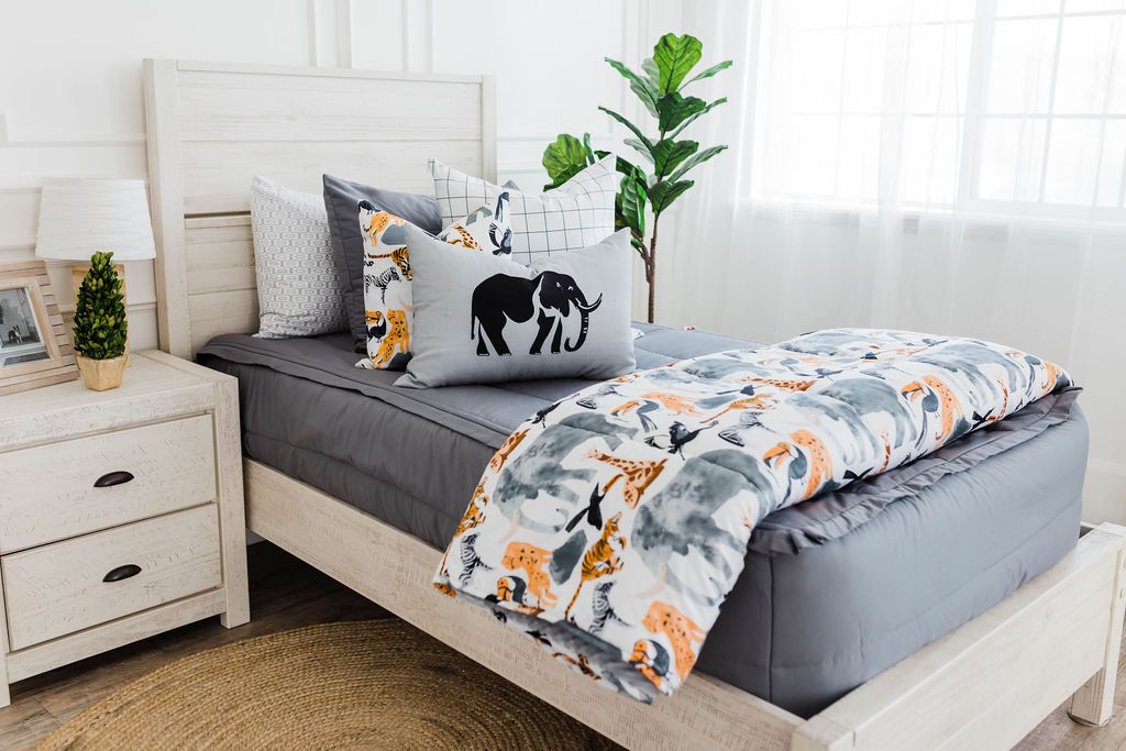 twin bed with Gray zipper bedding with white and black grid patterned euro, safari animal print pillow, gray lumbar with embroidered elephant and safari animal print blanket