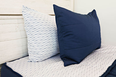 Enlarged view of a white and blue patterned pillowcase and a navy blue sham. 