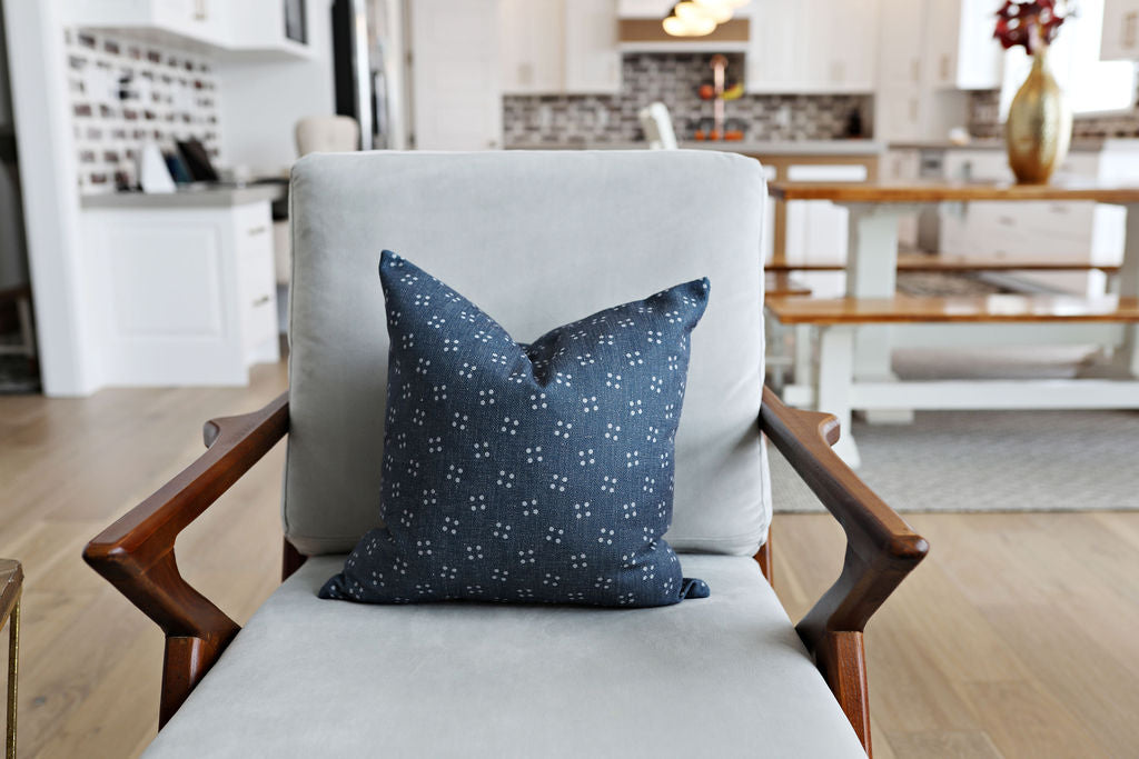 Blue denim pillow with white spots  sitting on a chair in a house