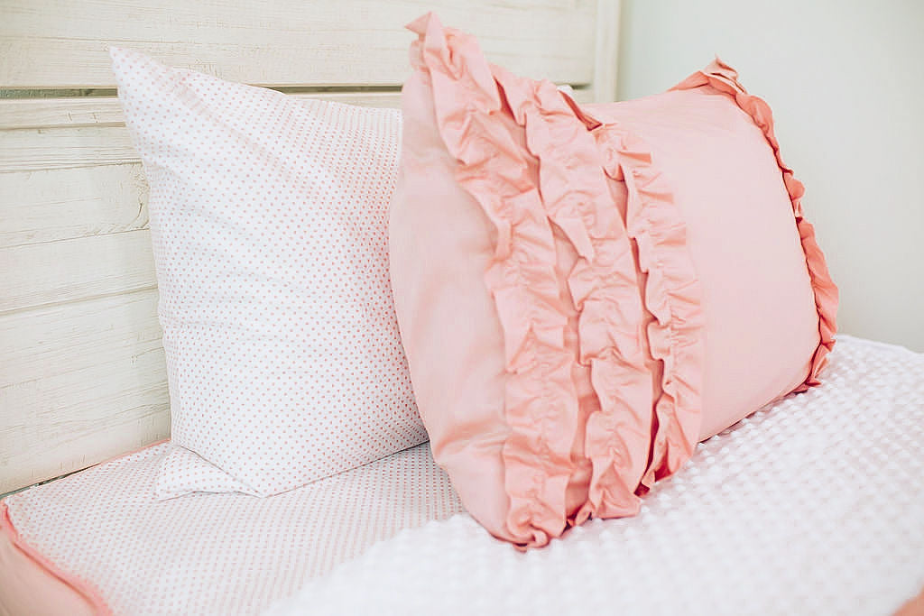 Enlarged side view of a white and pink polka dot pillowcase and a blush pink ruffled sham.