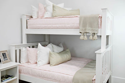 Pink zipper bedding on bunkbed. Deocorated with white, pink, and cream pillows and shams with brown cream throw blankets