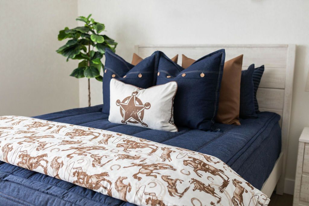 White blanket with cowboy and horseshoe design on blue zipper bedding with matching pillows