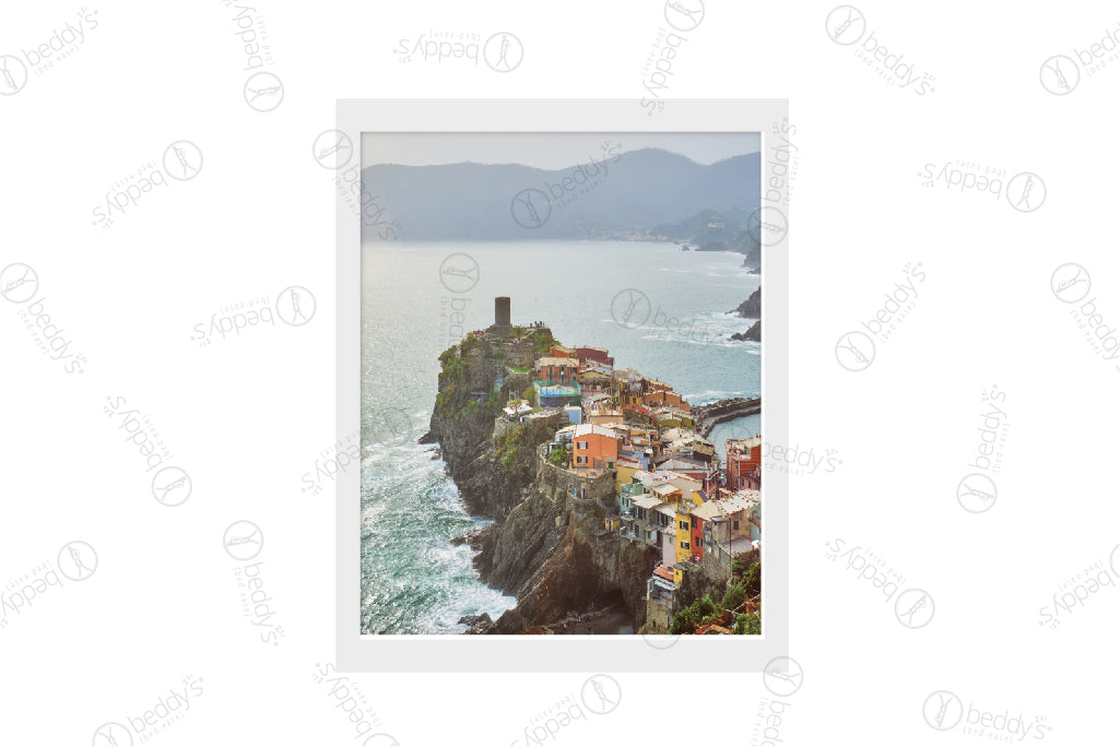 A small town on the edge of a cliffside island surrounded by water digital artwork showcased in a frame. 