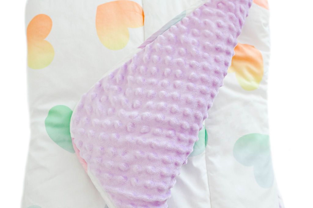 white blanket with ombre rainbow hearts with corner folded showing purple minky interior