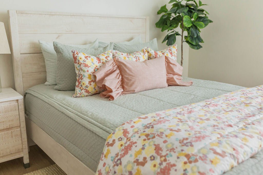 Green zipper bedding with pink and green pillows. Styled with matching floral blanket and pillows