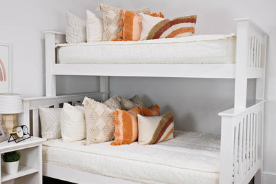 bunk bed with Cream bedding with textured rectangle design and dark cream textured euro, orange, textured pillow with tassels, rainbow lumbar and knitted chenille throw with pom poms