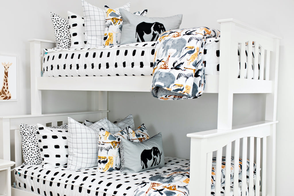 bunk bed with White bedding with black dashed lines white and black grid patterned euro, safari animal print pillow, gray lumbar with embroidered elephant and safari animal print blanket