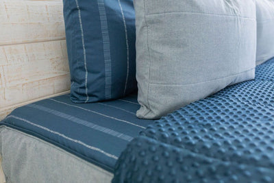 Dark and light blue pillows on a matching blue zipper bedding with the comforter pulled back. 
