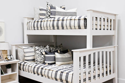 bunk bed with cream and black woven striped bedding, a white and black euro pillow, a medium black and cream textured pillow, a cream and black striped lumbar pillow