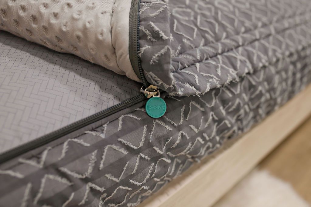 photo showing zipper edge on of gray textured bedding, gray arrow sheets and gray minky interior