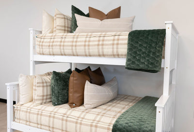 Cream and brown zipper bedding with matching and cream pillows. Decorated with brown leather pillow, cream lumbar pillow, and green matching pillow and blanket