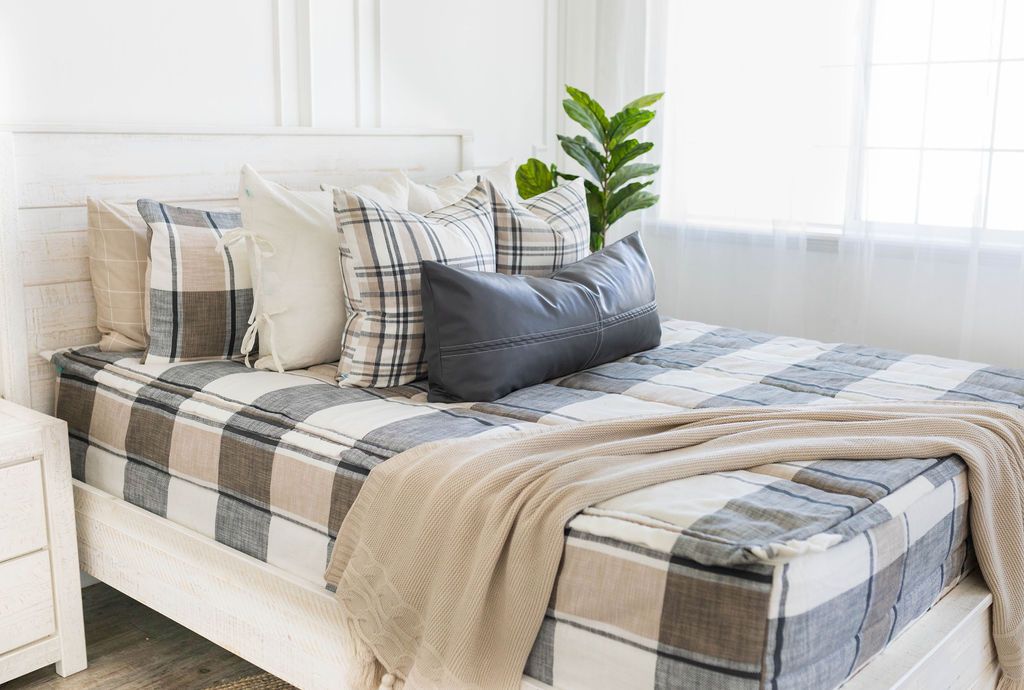 Black leather pillow on cream gray and white plaid zipper bedding with matching pillows and cream throw blanket