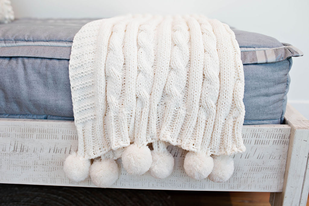 Enlarged view of a cream cable knit throw