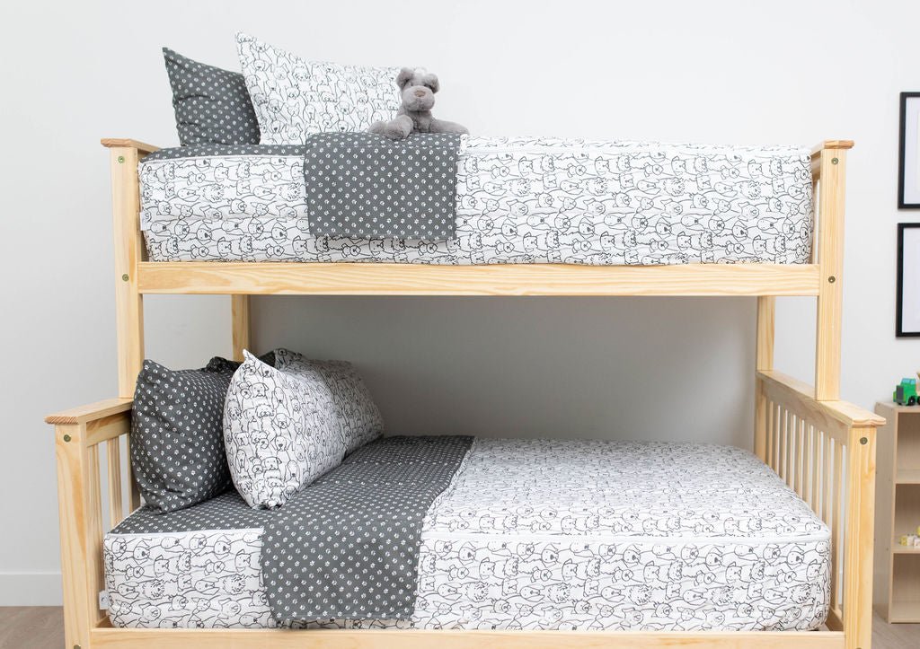 A bunk bed where both bunks are made with charcoal and white pattern dogs kids zipper bedding.