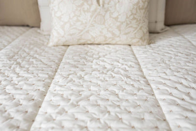 White and cream zipper bedding with brown stitching styled with matching white and cream pillows