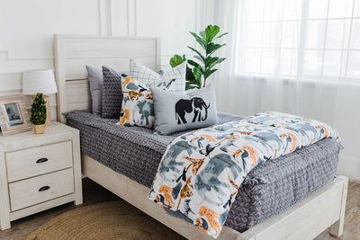 twin bed with Gray bedding with textured diamond and with white and black grid patterned euro, safari animal print pillow, gray lumbar with embroidered elephant and safari animal print blanket