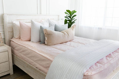 Pink zipper bedding with white pillowcases and shams. Pink and light blue shams and white throw blanket