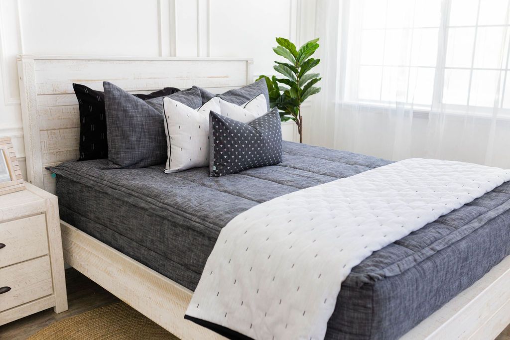Gray charcoal zipper bedding with gray, black and white pillows and white blanket