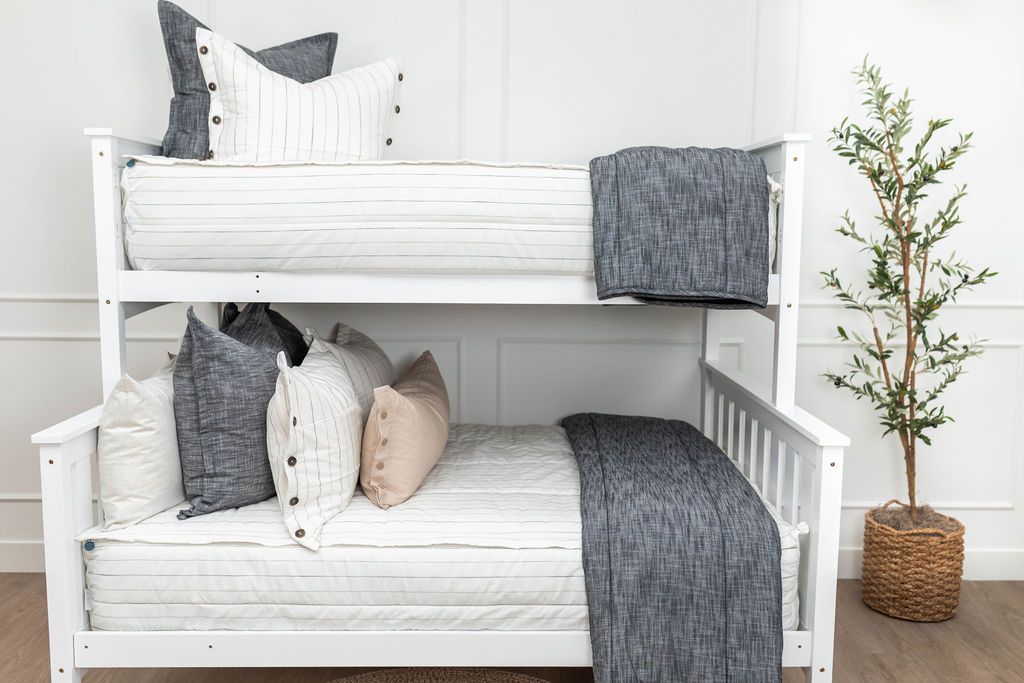 White zipper bedding on bunk beds with white, grey and tan pillows and grey blanket