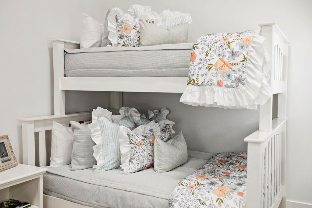 Twin bunk bed with Light gray zipper bedding with white and gray pillowcases and shams. Decorated with pastel floral pillow and matching blanket