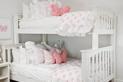 White bunk bed with white textured bedding, pink and white striped euro with ruffle, white and pink butterfly print pillow, pink plush butterfly pillow, and white and pink print blanket with white ruffle along the edge