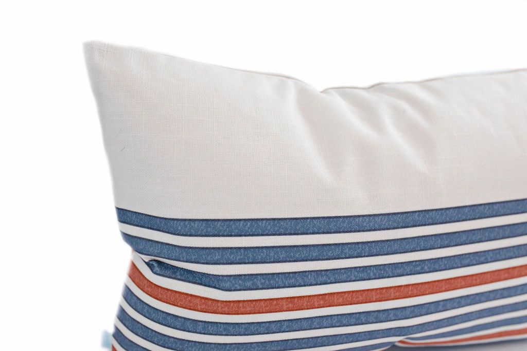 corner of Cream lumbar pillow with blue and orange stripe