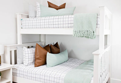 Bunk beds with White zipper bedding with teal lumbar pillow and thrown blanket with brown faux leather pillows