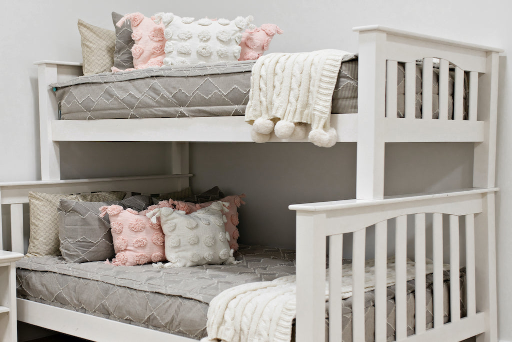 bunk bed with Taupe bedding with textured zig zag design and pink polka dot pillow, cream polka dot pillows and cream knitted chenille throw with pom poms