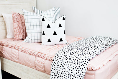 Blush pink bedding with white and black stripe euro, white and black grid euro, white pillow with black triangles and white and black dalmation print blanket