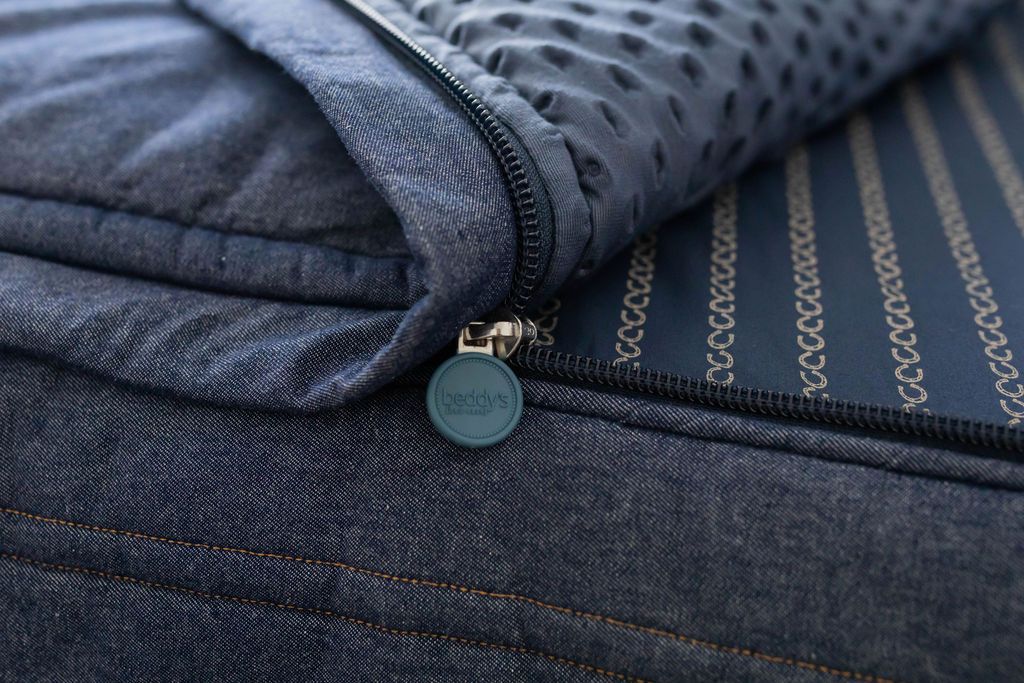 Close up of unzipped Dark blue zipper bedding revealing minky inner lining. Beddy's branded zipper pull tab