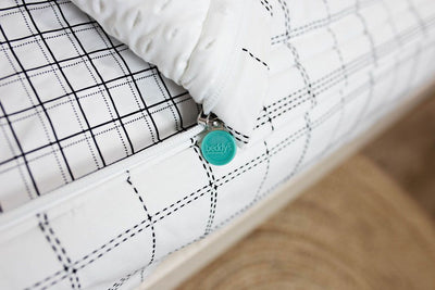 Photo showing zipper edge of white and black grid patterned bedding with white minky interior