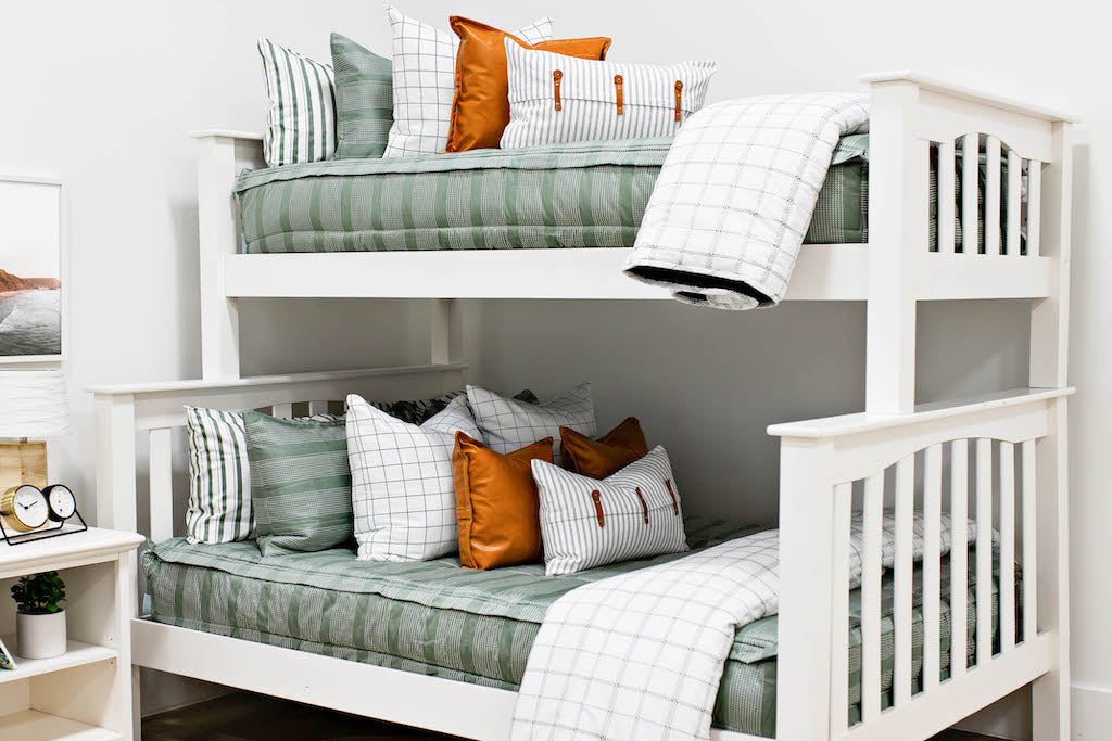 Queen bed with Green striped bedding with white and black grid euro, faux leather pillows, white and black striped lumbar with faux lather buckles and white and black grid pattered blanket