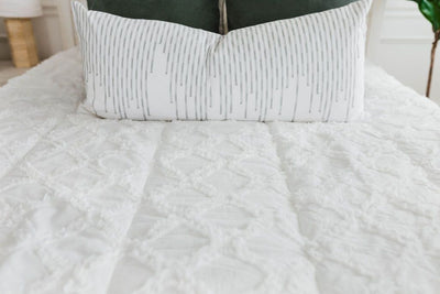 White bedding with textured diamond design and white XL lumbar with green stitching