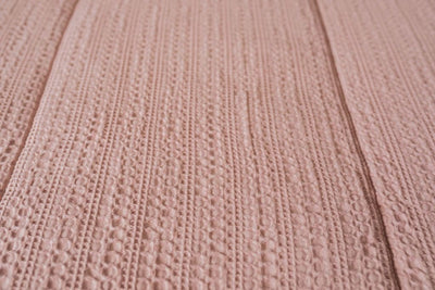 A close up view of the woven detail on pink zipper bedding.