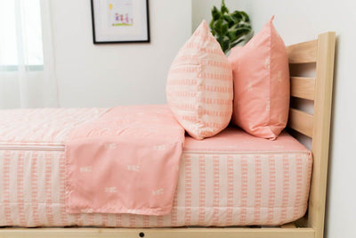 A side shot of a twin bed made with pink ballet shoes kids zipper bedding, the top unzipped and pulled back slightly and two pillows at the head of the bed.