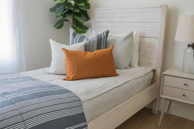 A twin bed made with light gray waffle textured zipper bedding and gray striped neutral pillows and matching blanket.