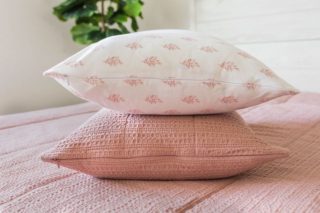 A pink zipper bedding made with the matching pillows stacked in the middle of the bed. 